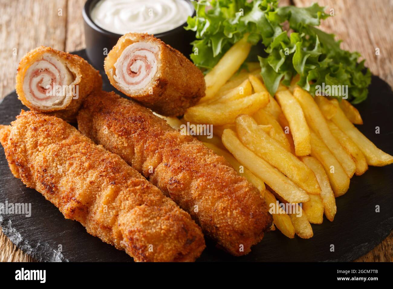 Flamenquines cordobeses pork rolls with French fries closeup in the slate plate on the table. Horizontal Stock Photo