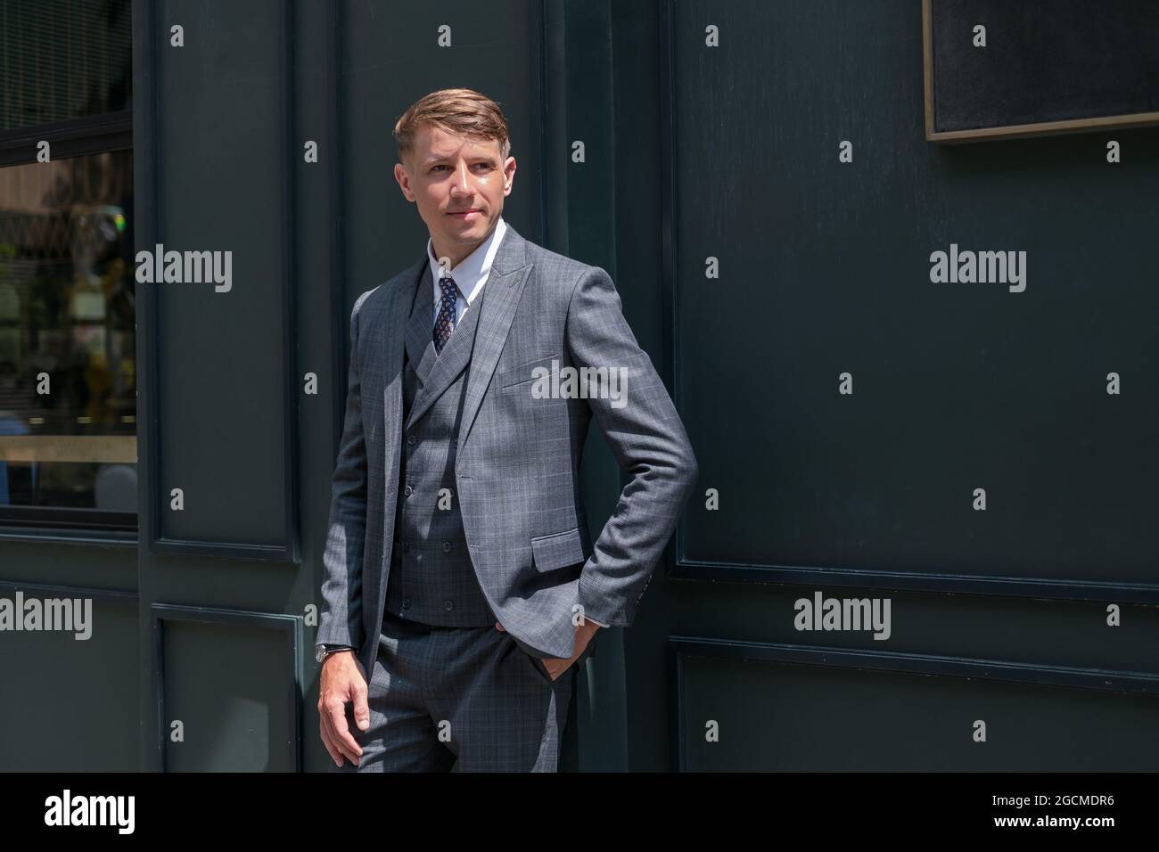 Handsome businessman in grey formal suit standing on derk green background. Model posing. High quality photo Stock Photo