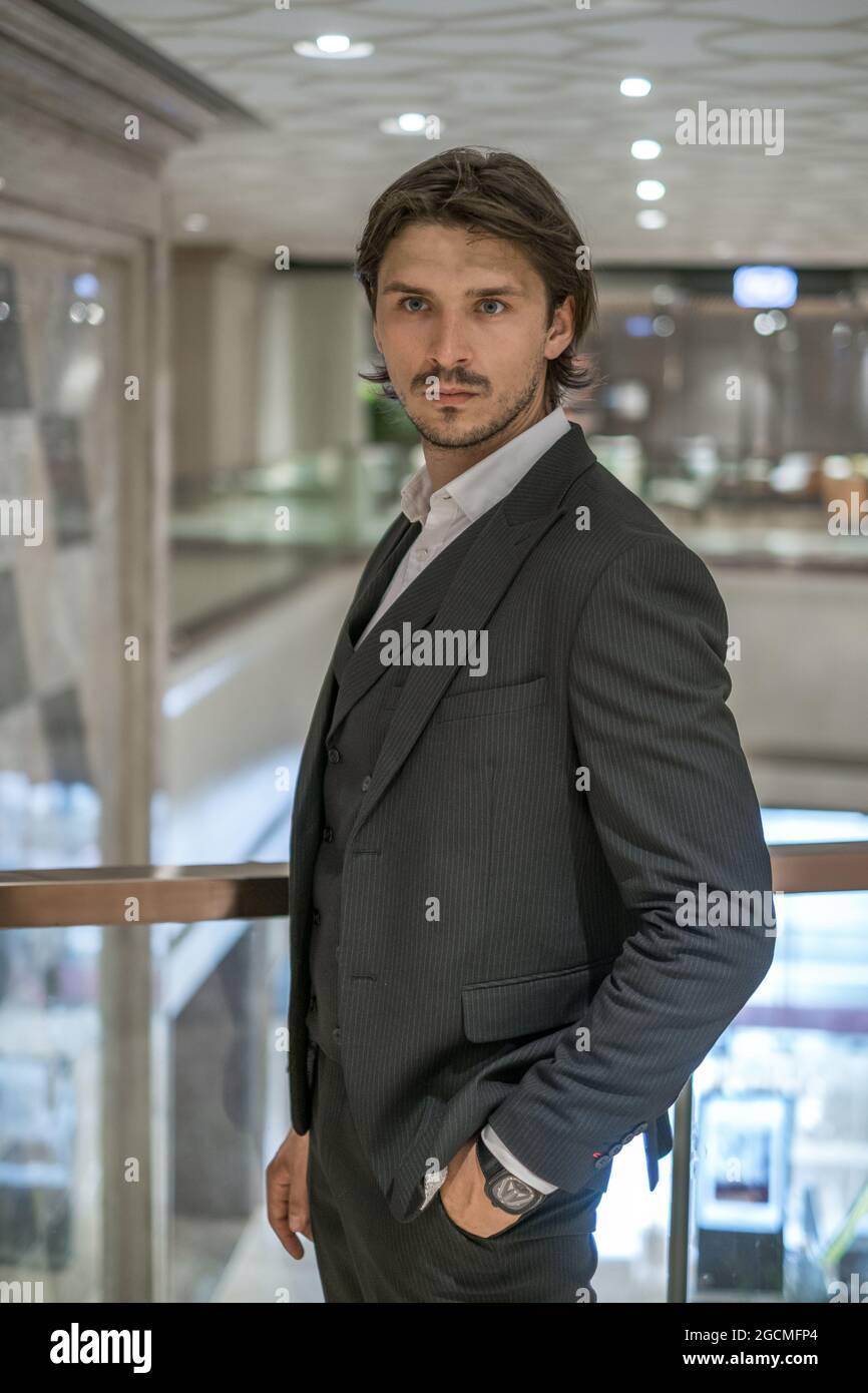 Portrait of handsome man in formal black suit standing in modern building. High quality photo Stock Photo