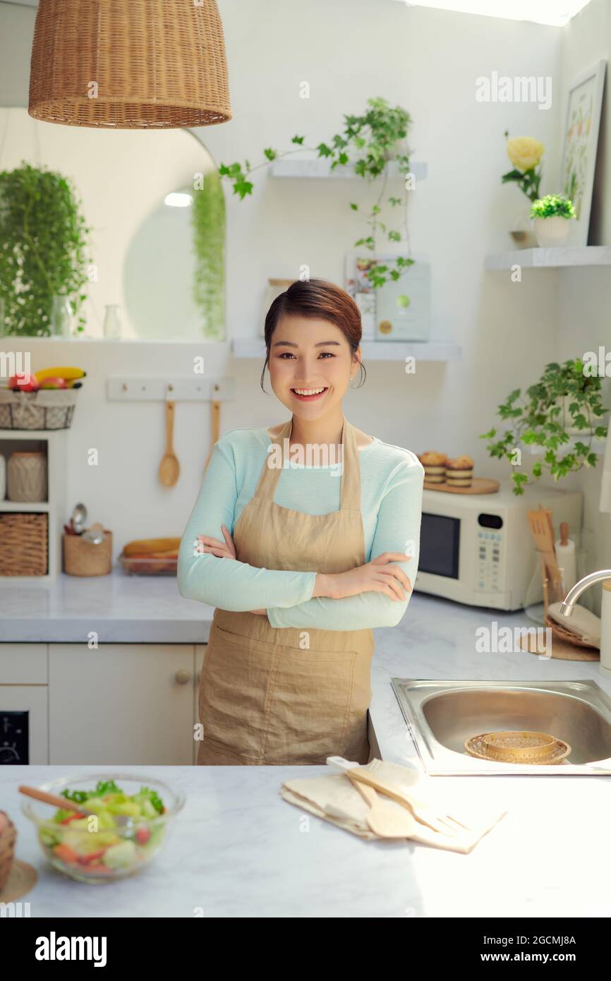 Asian cute woman in an apron standing and cross her arm across her chest with elegance gesture and self-confident. Stock Photo