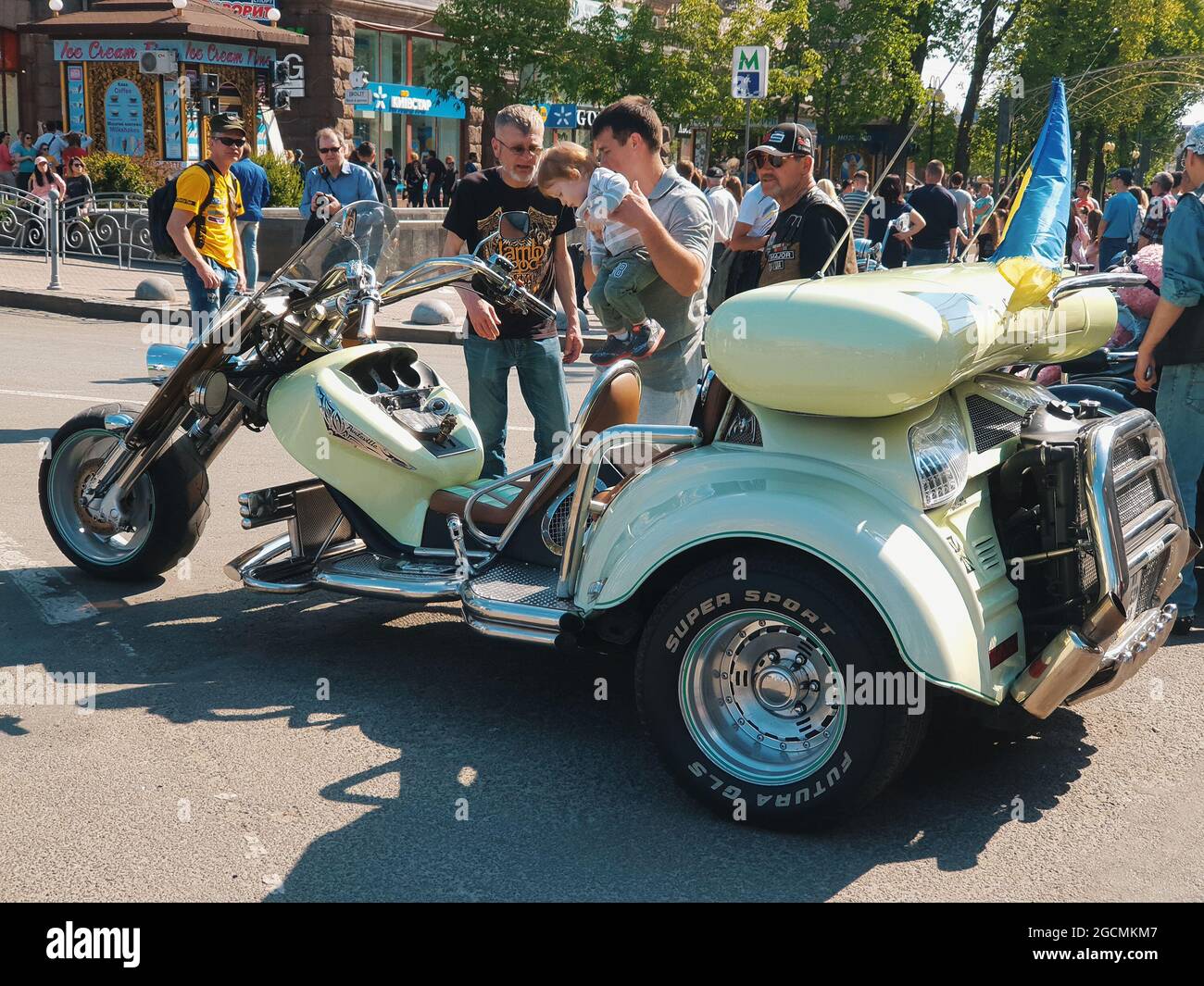 Kiev, Ukraine-April 29, 2018: Group of people curiously looking at and experiencing parked spectacular three wheeler motorbike on Kreschatik street in Stock Photo