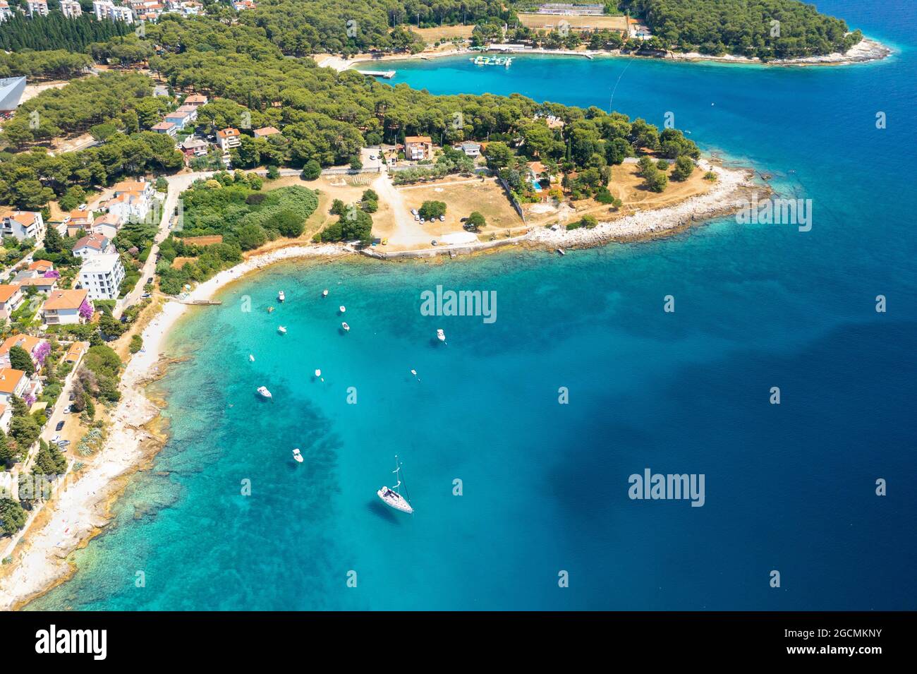 Aerial view of sailboat and small boats or yachts in the turquoise waters of the Adriatic sea close to beach of island. Stock Photo