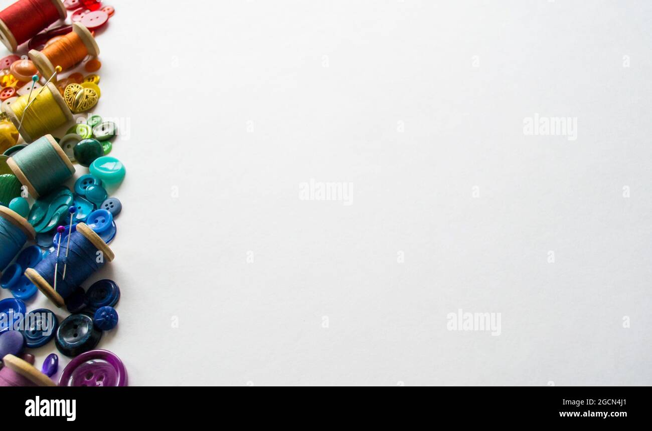 A lot of buttons and reels with colorful threads, laid out on a white ...