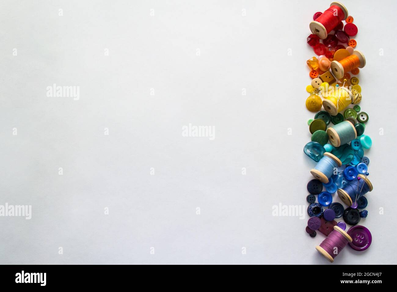 A lot of buttons and reels with colorful threads, laid out on a white ...