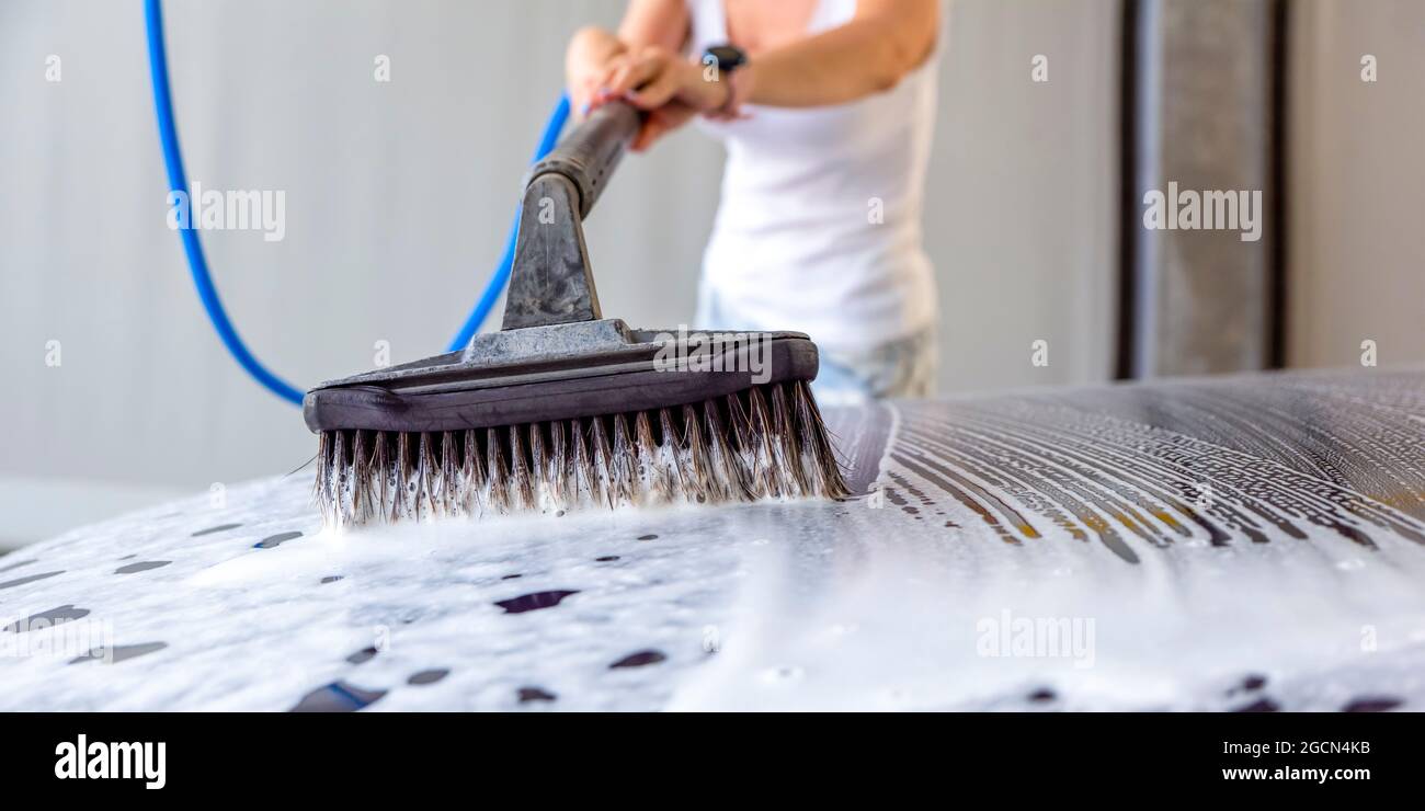 Car wash, car wash with active foam. Vehicle care. Woman washing car