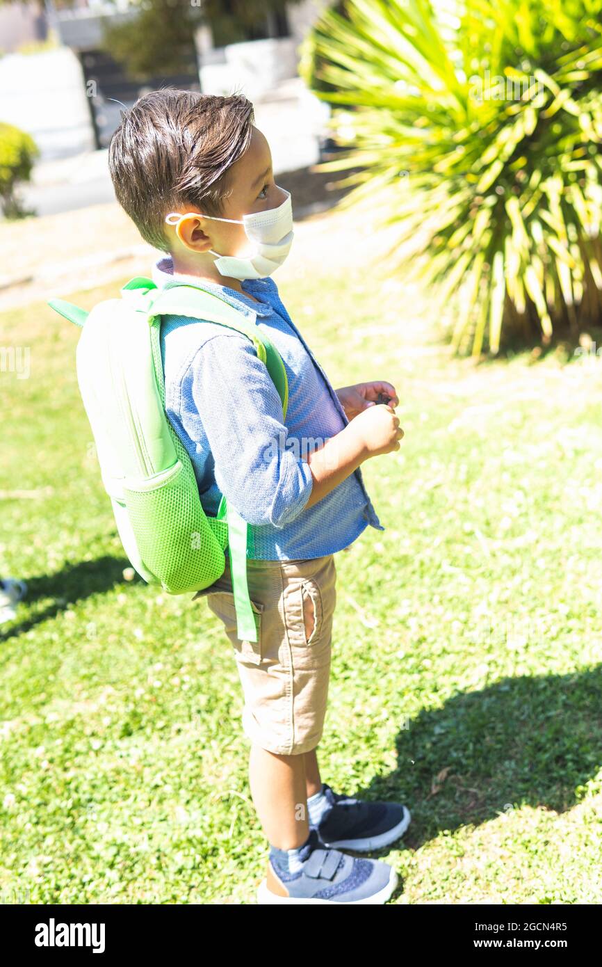 Vertical portrit of a boy with mask and backpack in a park Stock Photo