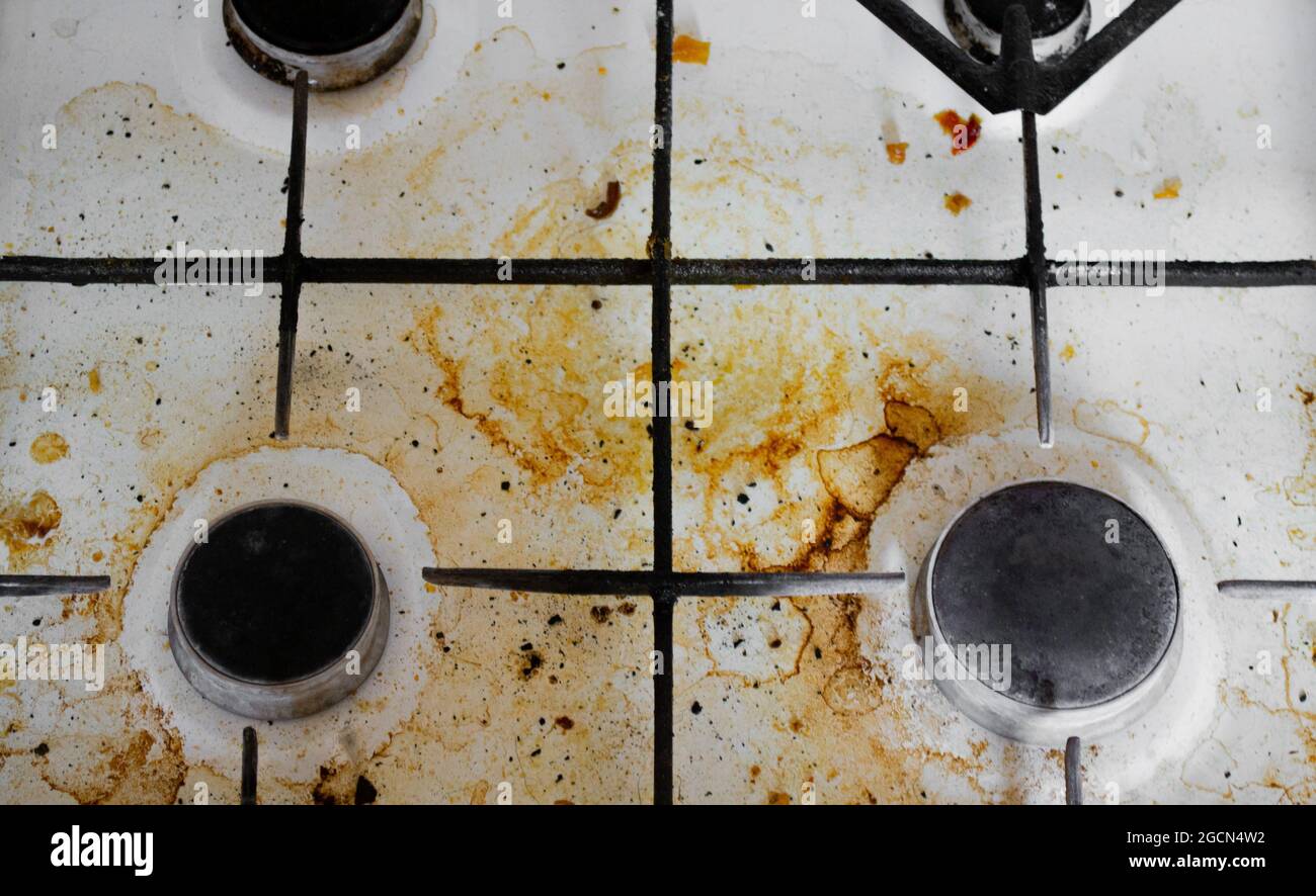 Top view of a very dirty white gas stove with yellow streaks and greasy