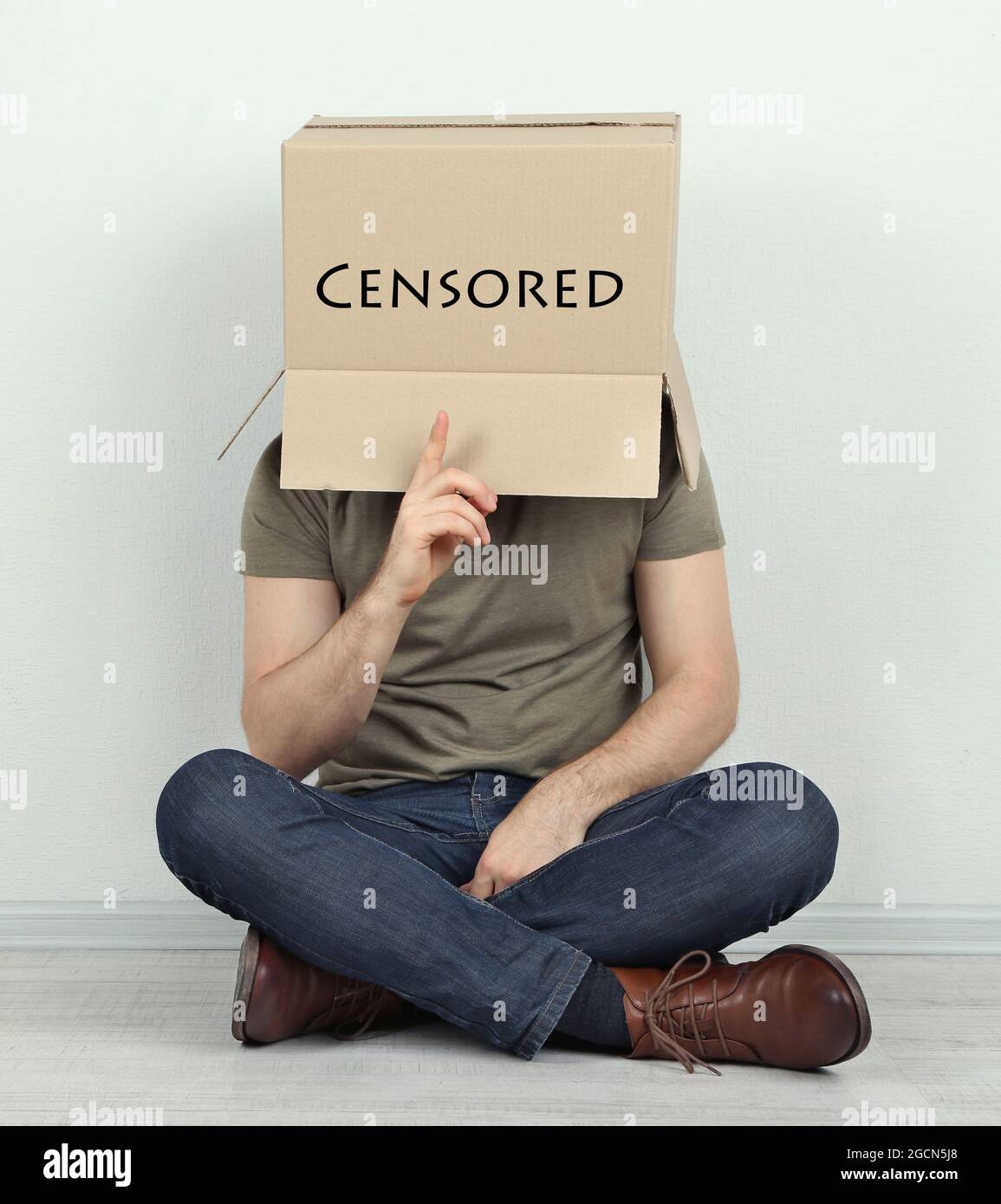 Man with cardboard box on his head sitting on floor near wall Stock ...