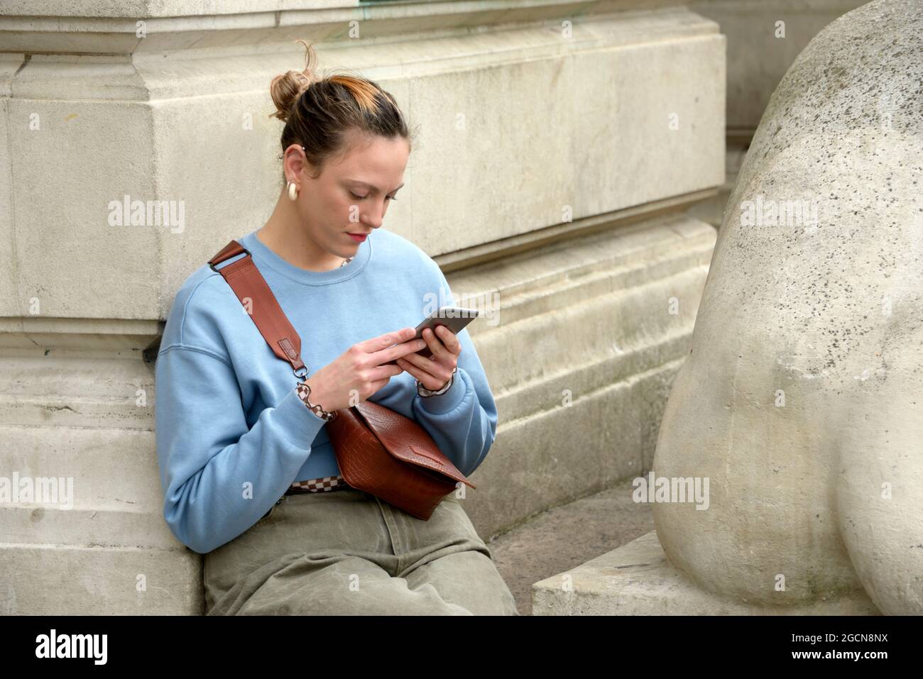 Young lady in pale blue top, studying mobile phone Stock Photo