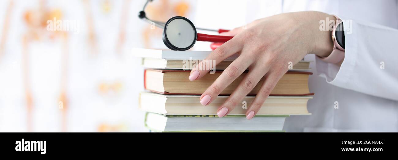 Doctor hands are holding stack of books and stethoscope Stock Photo - Alamy