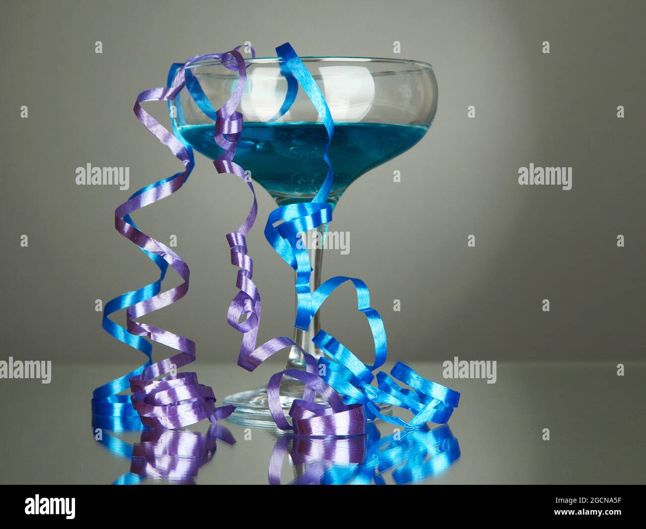Glass of cocktail and streamer after party on gray background Stock ...