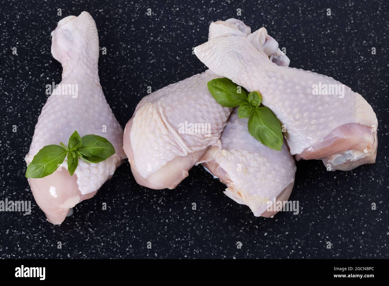 raw chicken drumsticks on a wooden cutting board. Raw chicken meat top