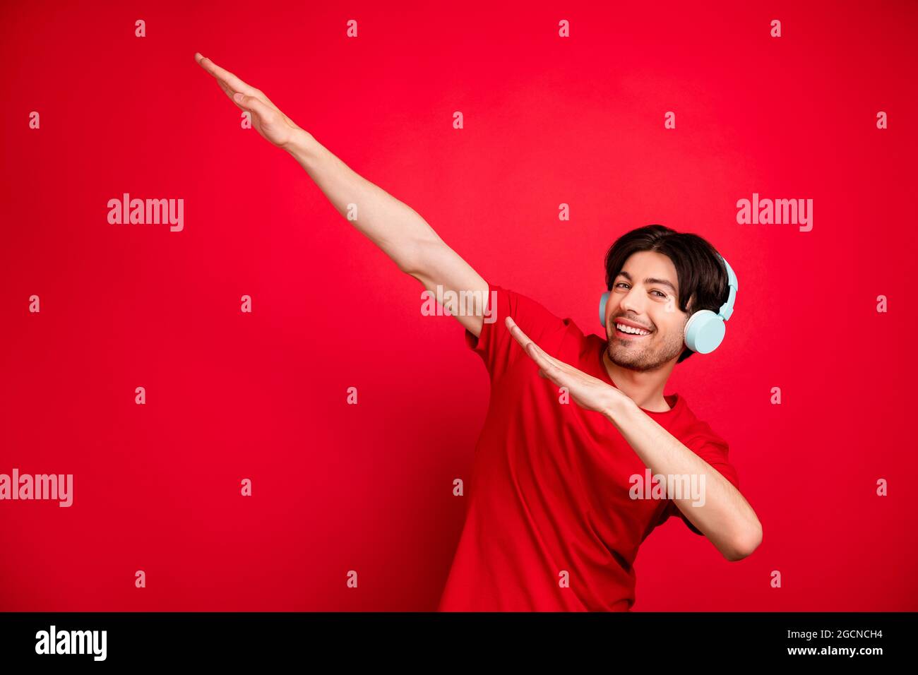 Photo of young man happy positive smile listen music headphones dance dab  hip-hop isolated over red color background Stock Photo - Alamy