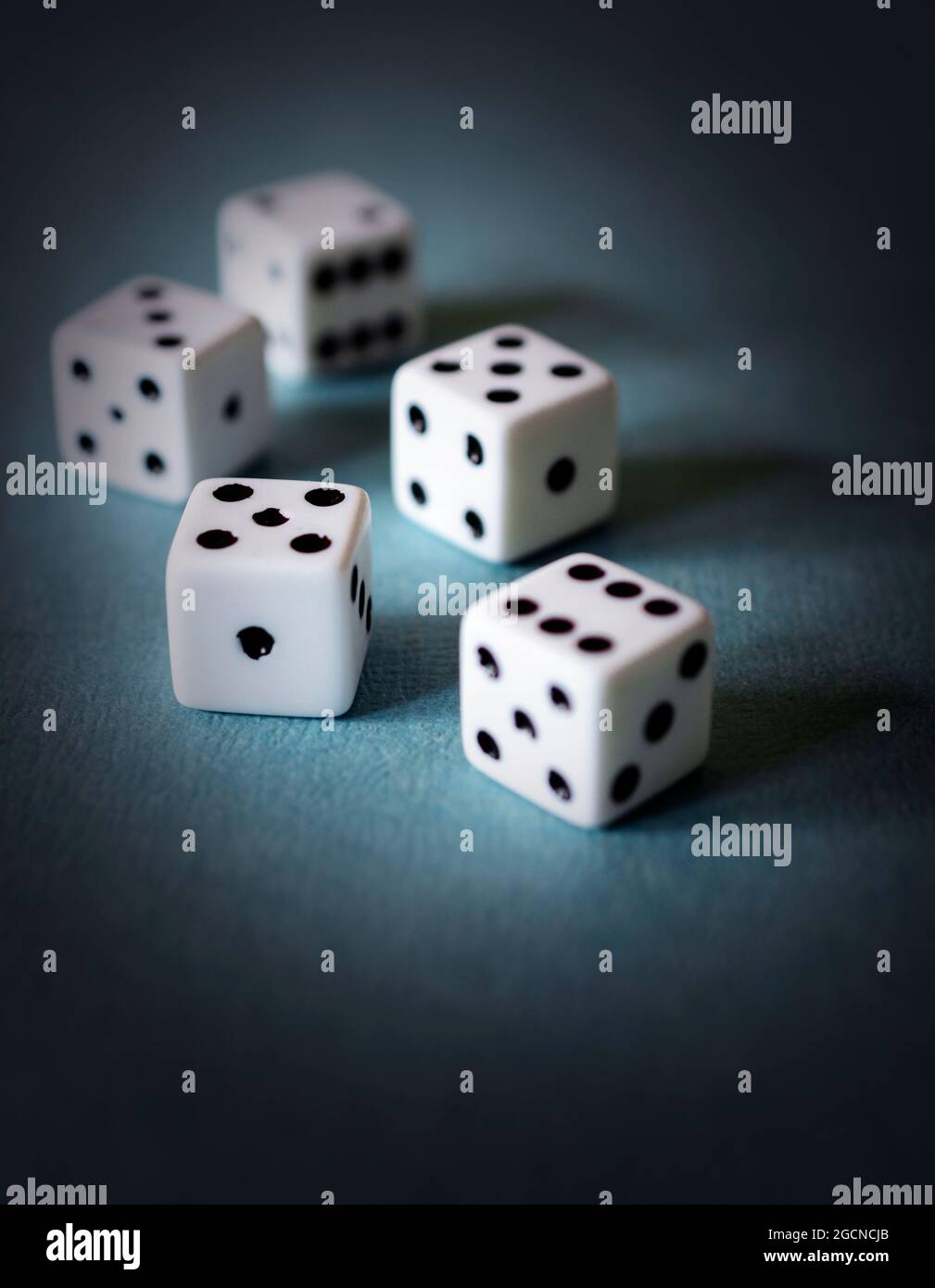Five dice on a textured teal board.  Dramatic edit. Stock Photo
