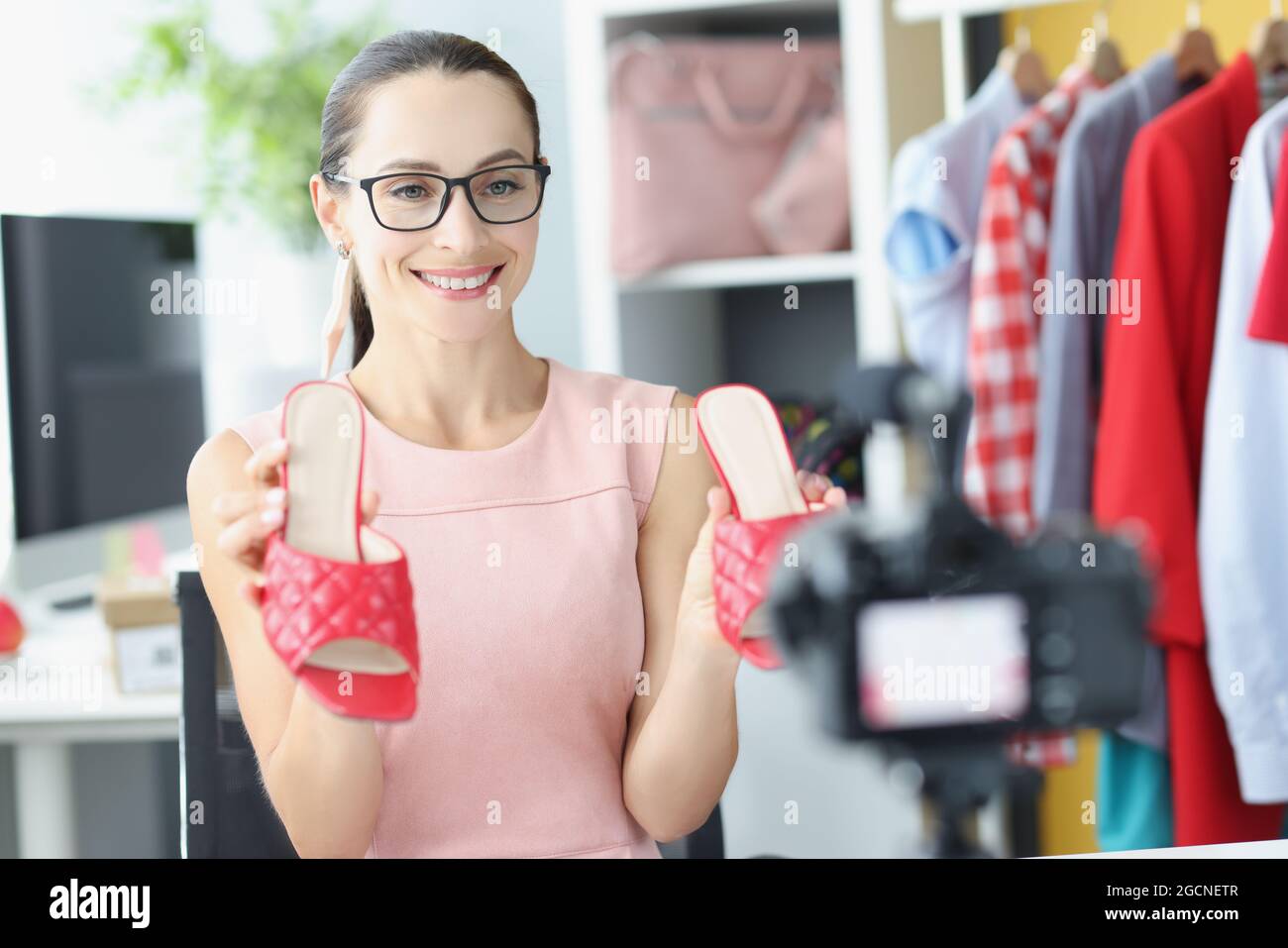 Woman blogger demonstrates leather red sandals to camera Stock Photo
