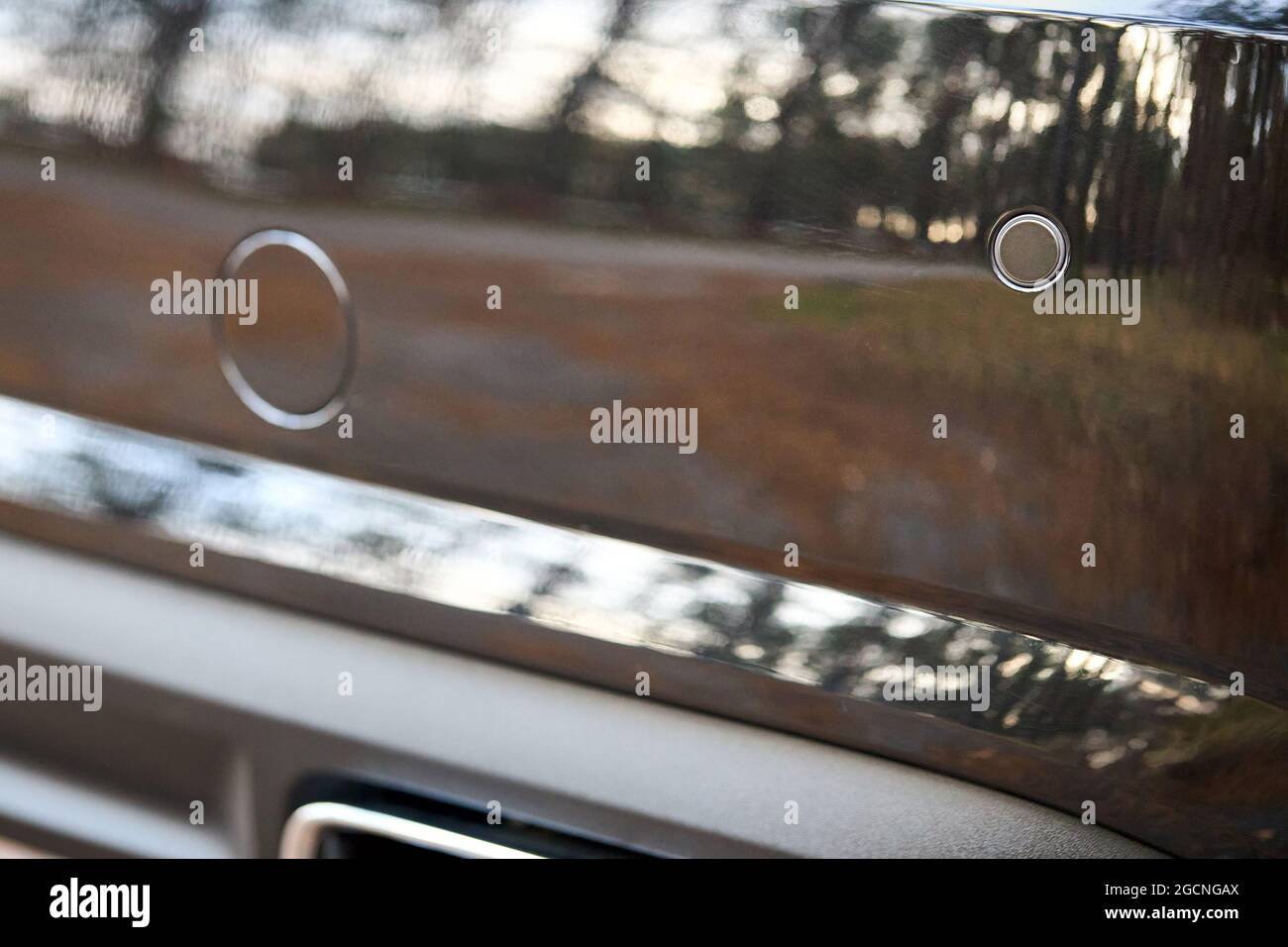 Selective focus on rear bumper parking sensors near exhaust pipe at