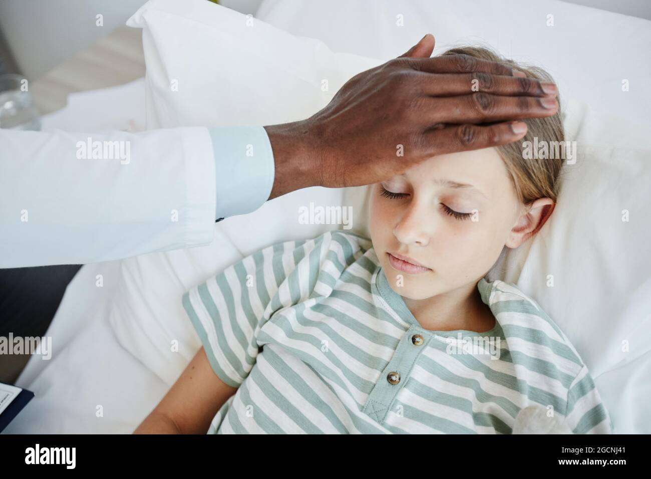 Close up of African-American doctor caring for little girl lying in hospital bed Stock Photo