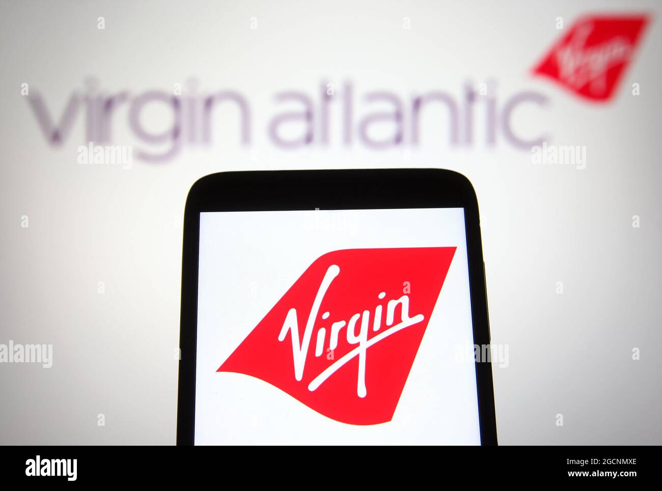 In this photo illustration a Virgin Atlantic logo is seen on a smartphone and a pc screen. Stock Photo