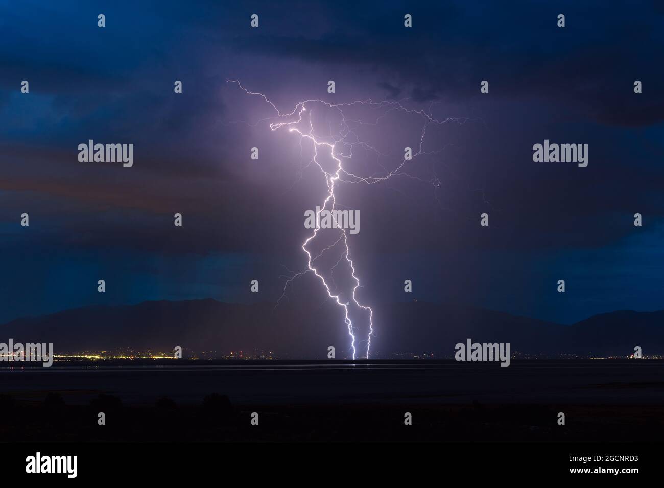 Vibrant lightning strike over Salt Lake City, Utah as a thunderstorm drifts across the Great Salt Lake into the foothills of the Wasatch Range Stock Photo