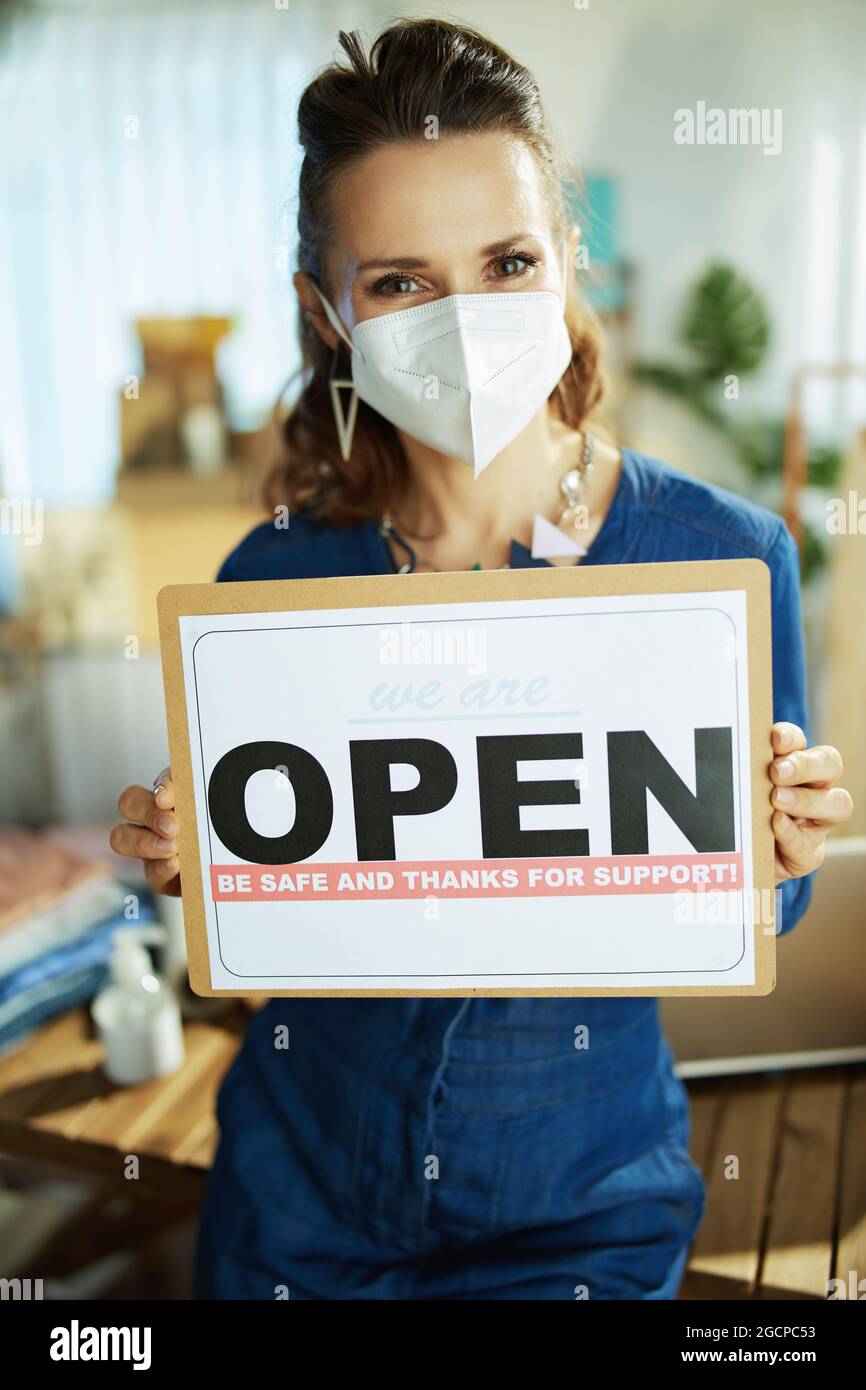 trendy 40 years old small business owner woman with ffp2 mask and open after covid sign in the office. Stock Photo