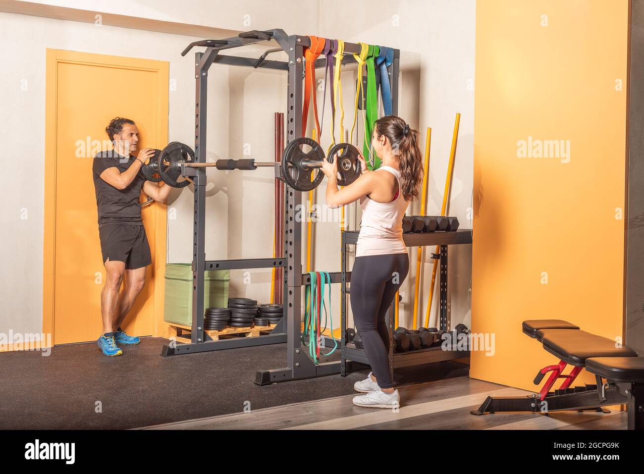 Man and woman putting weight plate on bar in gym Stock Photo Alamy