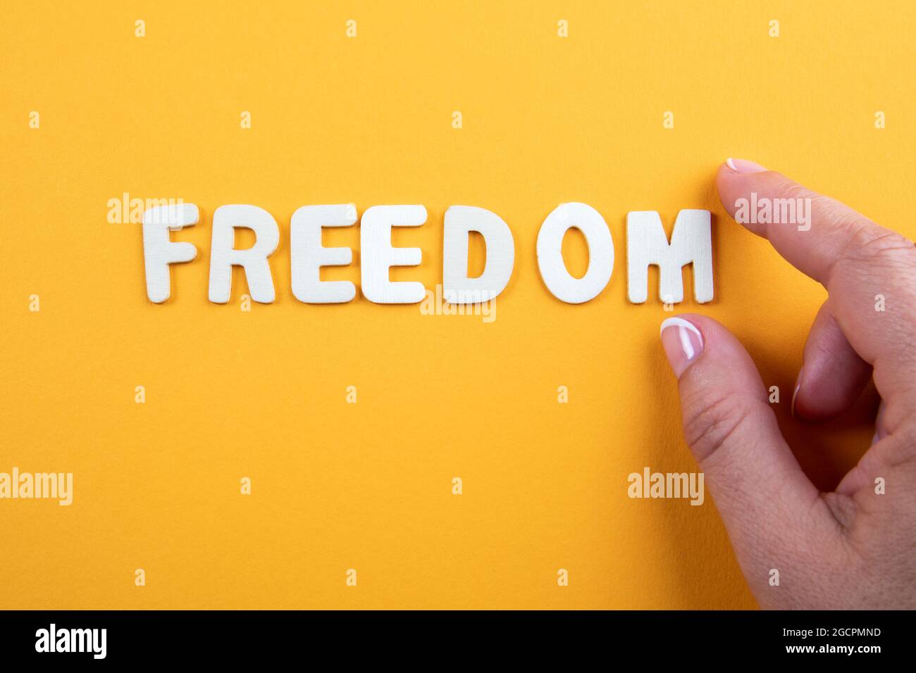 FREEDOM. Word from white letters with a woman's hand on yellow ...