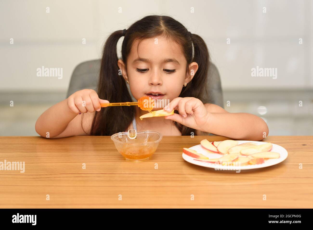 Little Girl Eating Apple With Honey. Healthy Eating For Children. Stock Photo