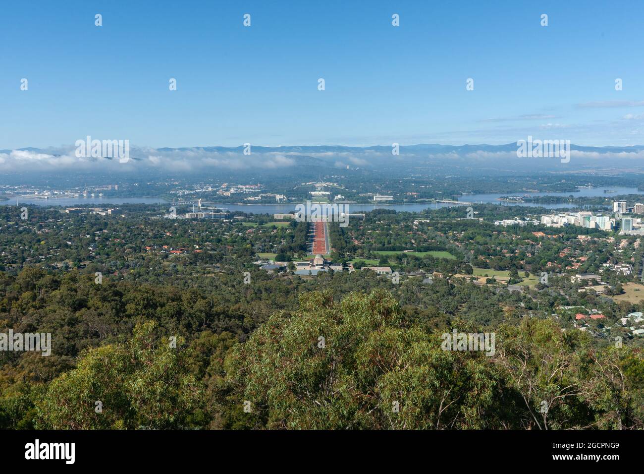 View from Mount Ainslie behind Australian War Memorial Museum building along red sealed ANZAC Parade across Molonglo River to parliament buildings und Stock Photo