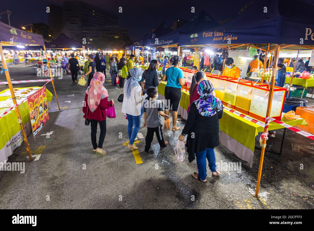 Street food night market at  Putrajaya, near Kuala Lumpur. Muslim Malay family walks between the food stands and carries her purchases in plastic bags Stock Photo