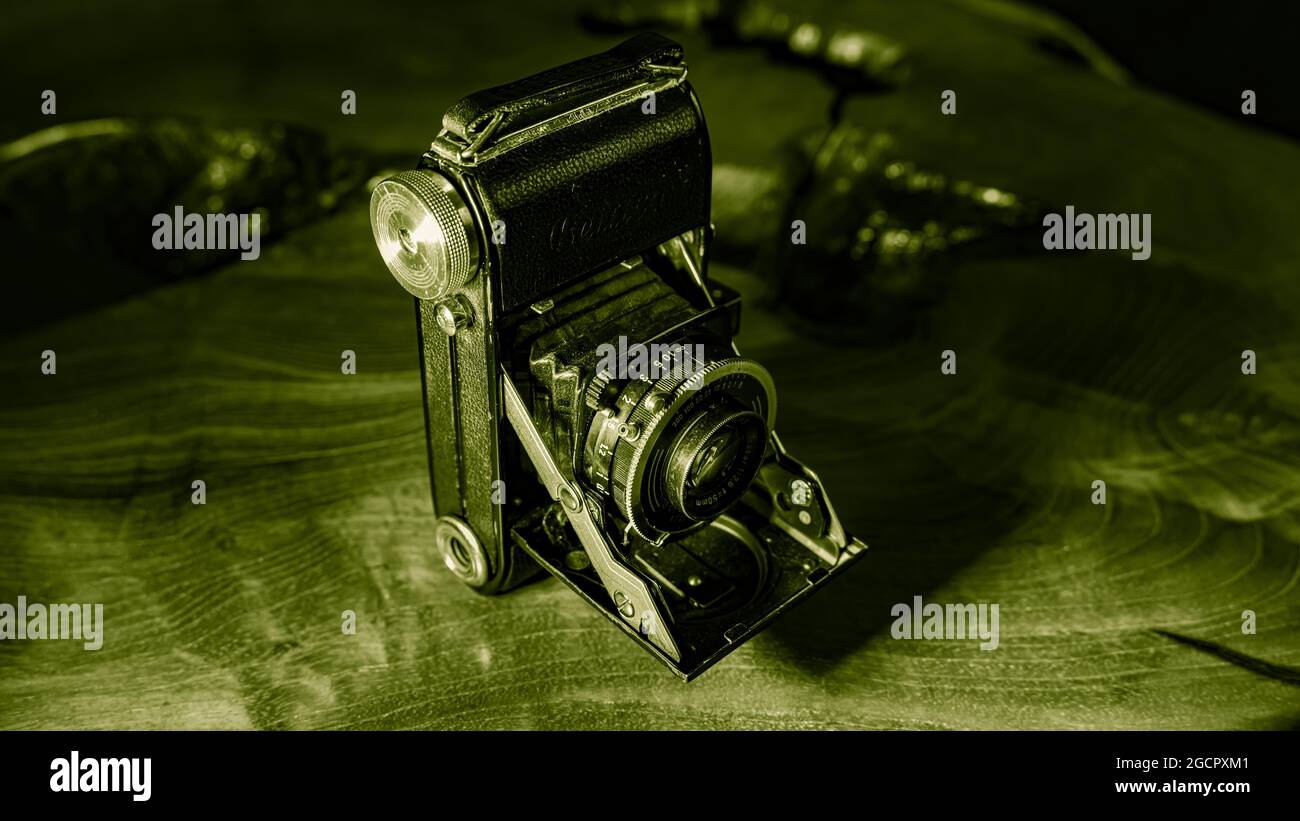 Leipzig, Saxonia, Germany - October 1, 2020: Old scratched and dusty photo camera, with foldable original Carl Zeiss Lens, standing on a antik wooden Stock Photo