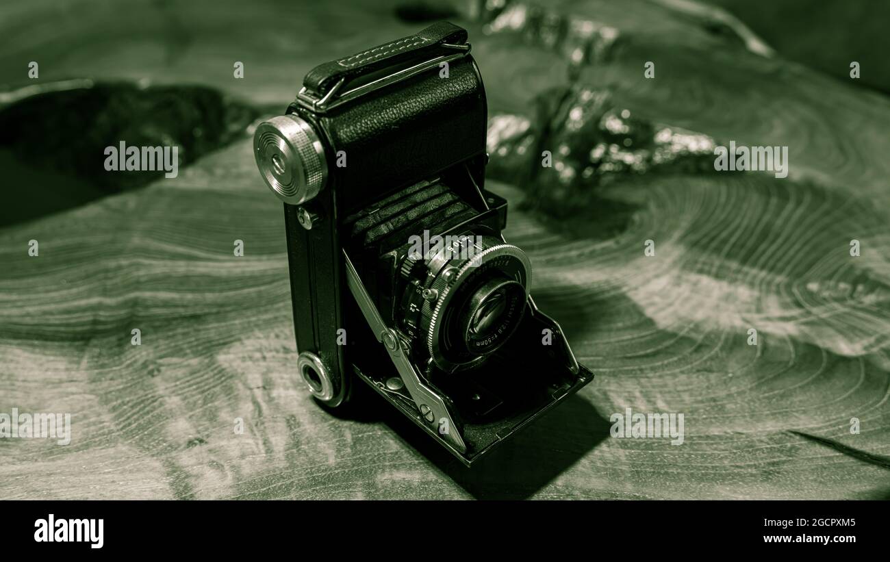 Leipzig, Saxonia, Germany - October 1, 2020: Old scratched and dusty photo camera, with foldable original Carl Zeiss Lens, standing on a antik wooden Stock Photo