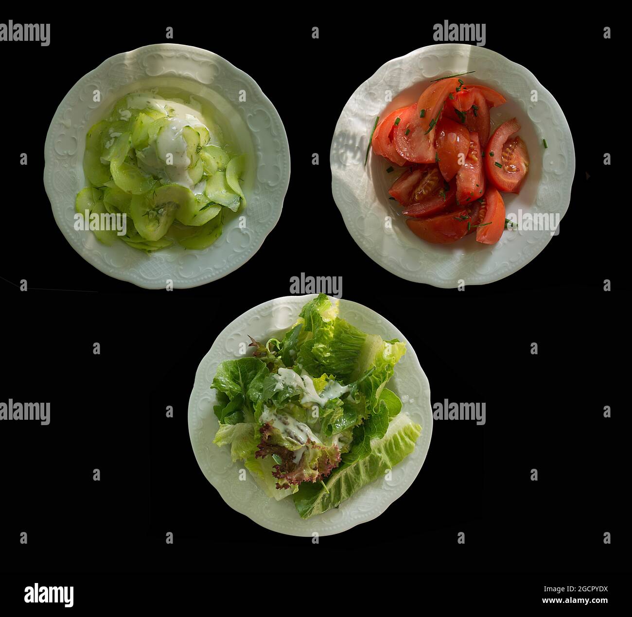 Three different salad plates, cucumber salad, tomato salad and leaf salad on a black background, Bavaria, Germany Stock Photo