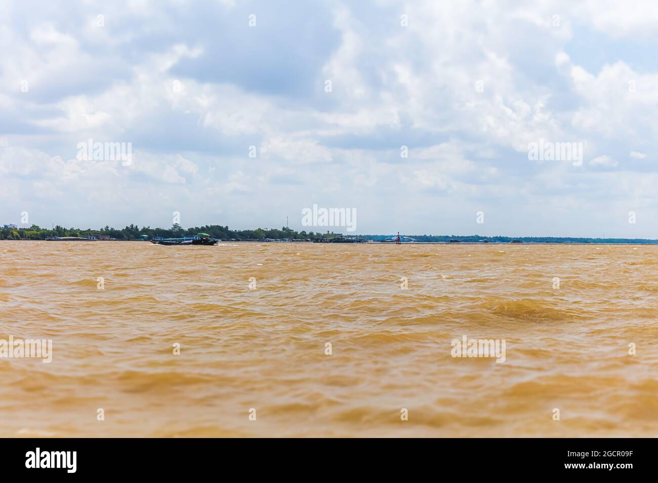 On the Mekong river at Vietnam. Crossing the Mekong river near the city of Saigon or Ho Chi Ming City. Water splashing under blue sky with white cloud Stock Photo