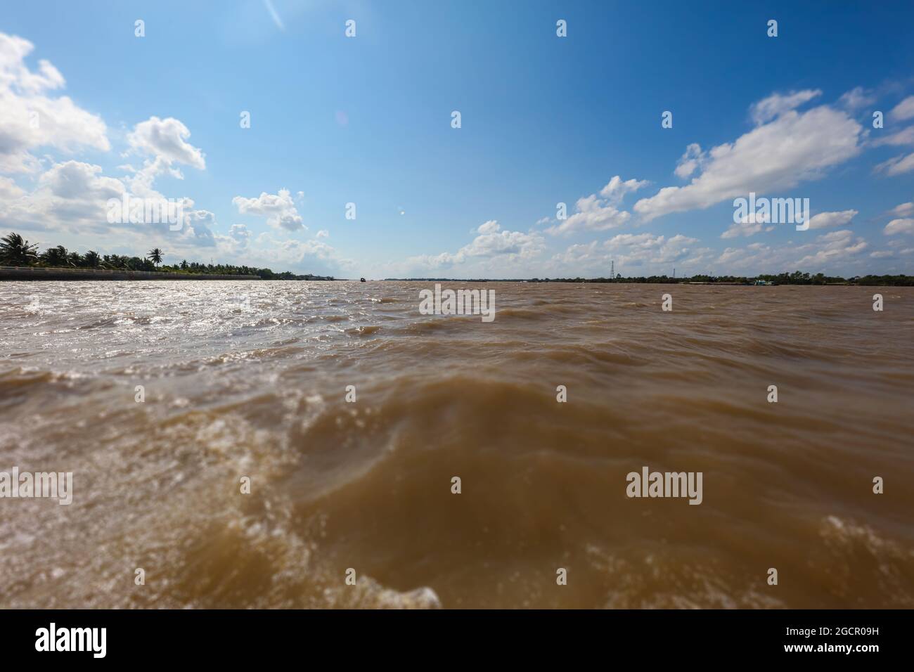 On the Mekong river at Vietnam. Crossing the Mekong river near the city of Saigon or Ho Chi Ming City. Water splashing under blue sky with white cloud Stock Photo