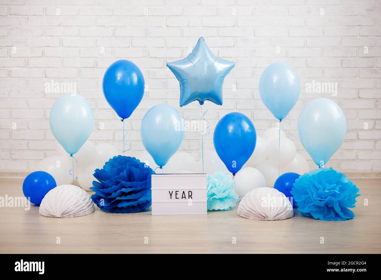 baby boy first birthday party decoration - blue air balloons and paper  balls over white brick wall background Stock Photo - Alamy