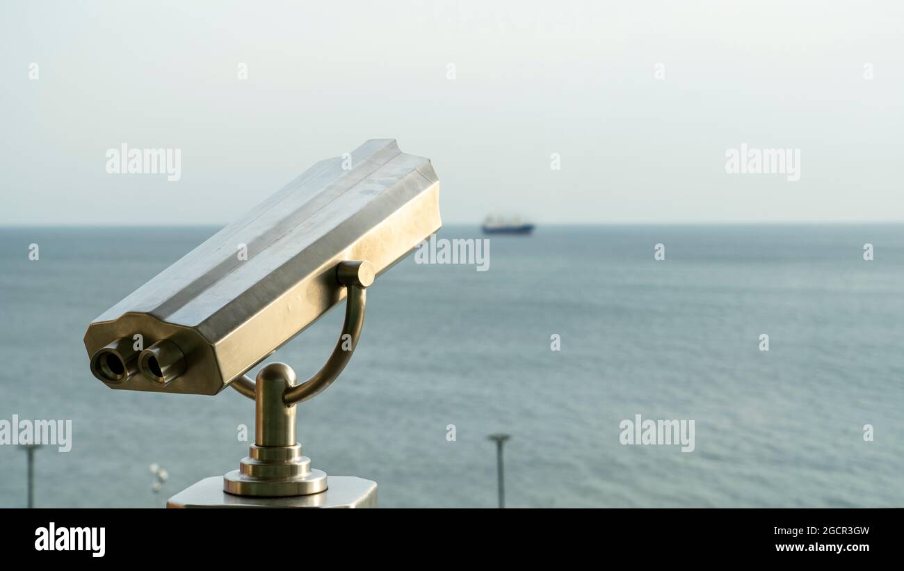 Close-up of coin-operated binoculars against sea during sunset Stock Photo