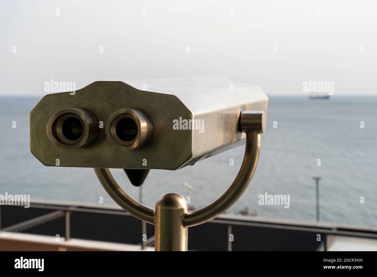 Close-up of coin-operated binoculars against sea during sunset Stock Photo