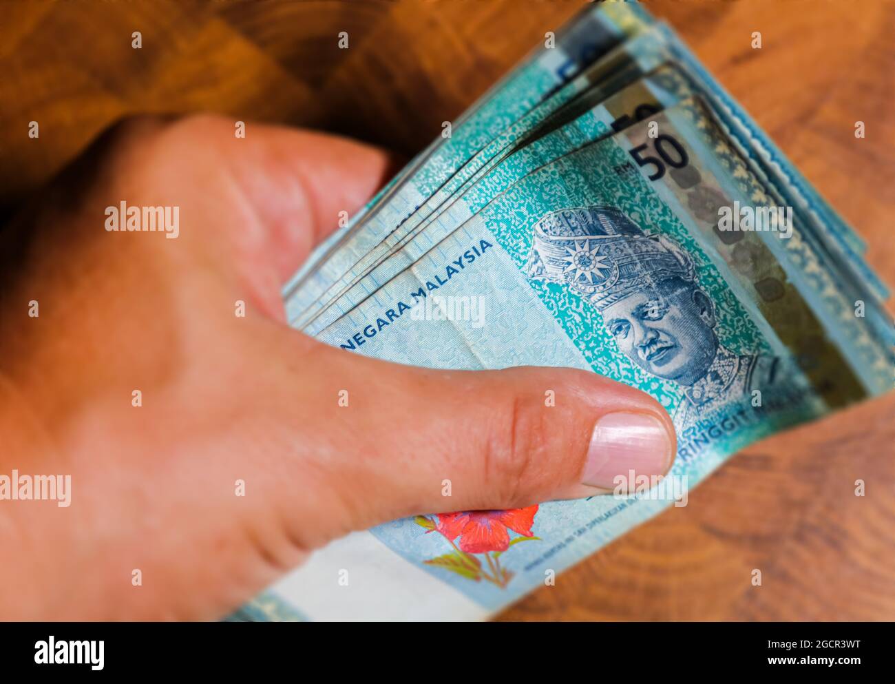 A collection of Fifty malaysian ringgit banknotes in a male hand. Man hand show Malaysia Ringgit banknotes. Boys hands holding money of Malaysia. Asia Stock Photo