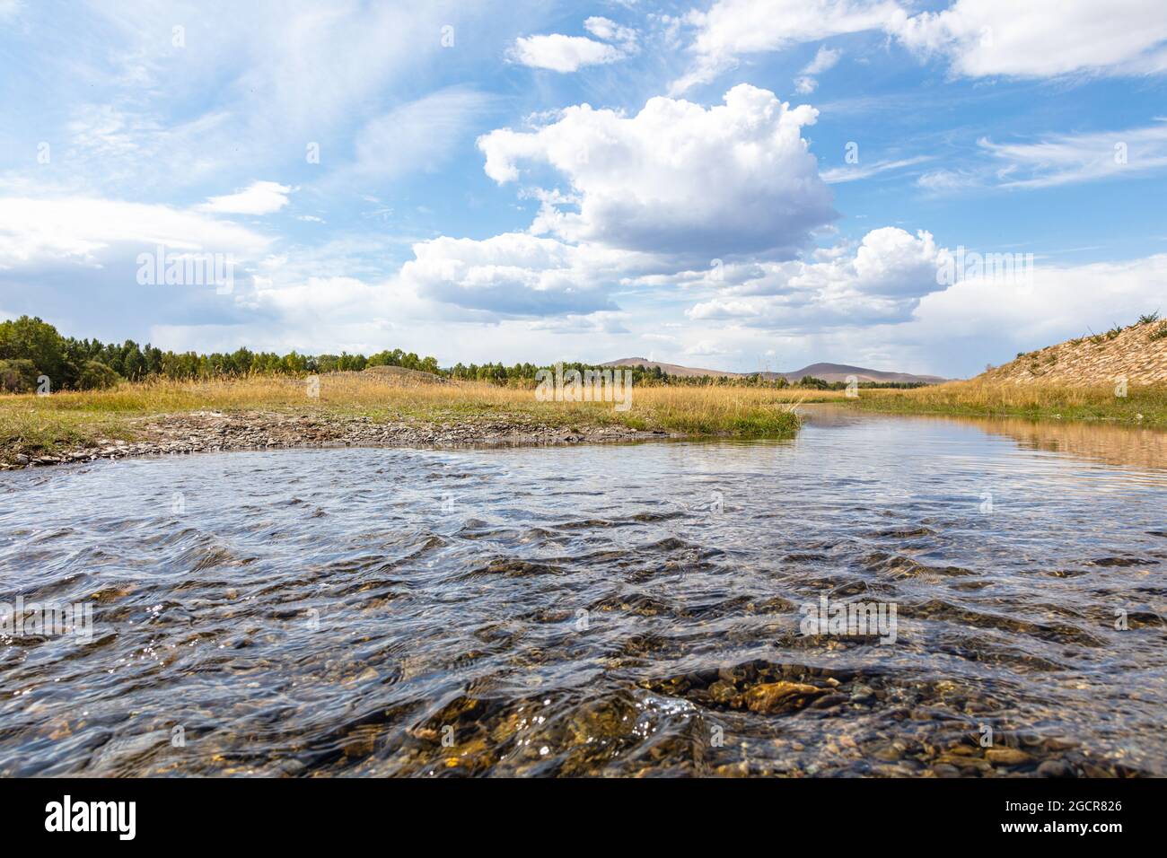 Highland Rivers A highland river valley with yellow grass under white clouds and blue ...