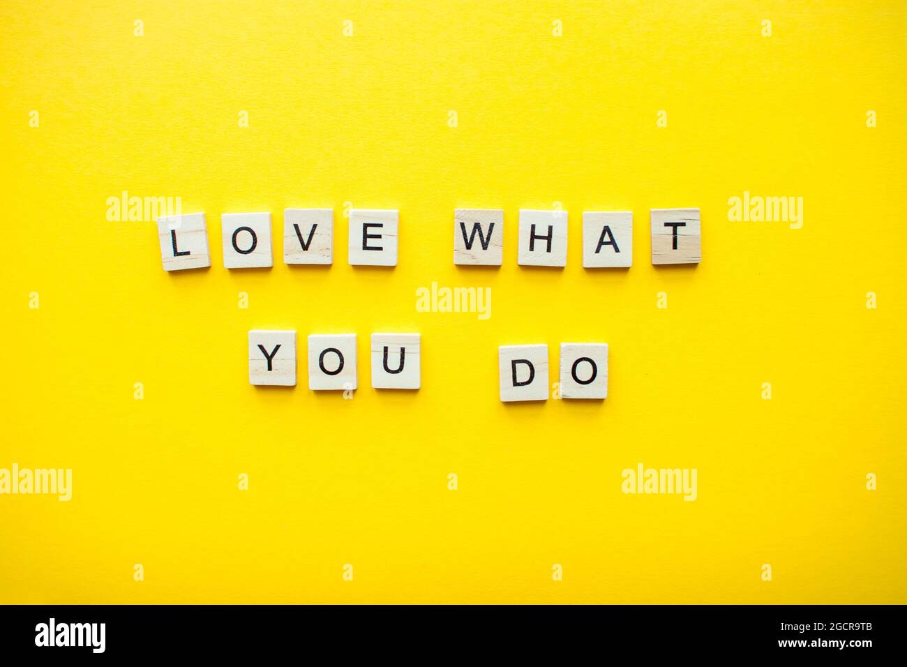 The inscription love what you do from wooden blocks on a bright yellow background Stock Photo