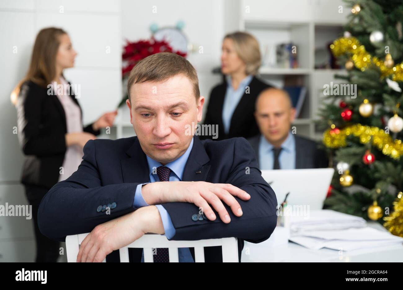 Business team tensely solving problems in office with offended man foreground Stock Photo