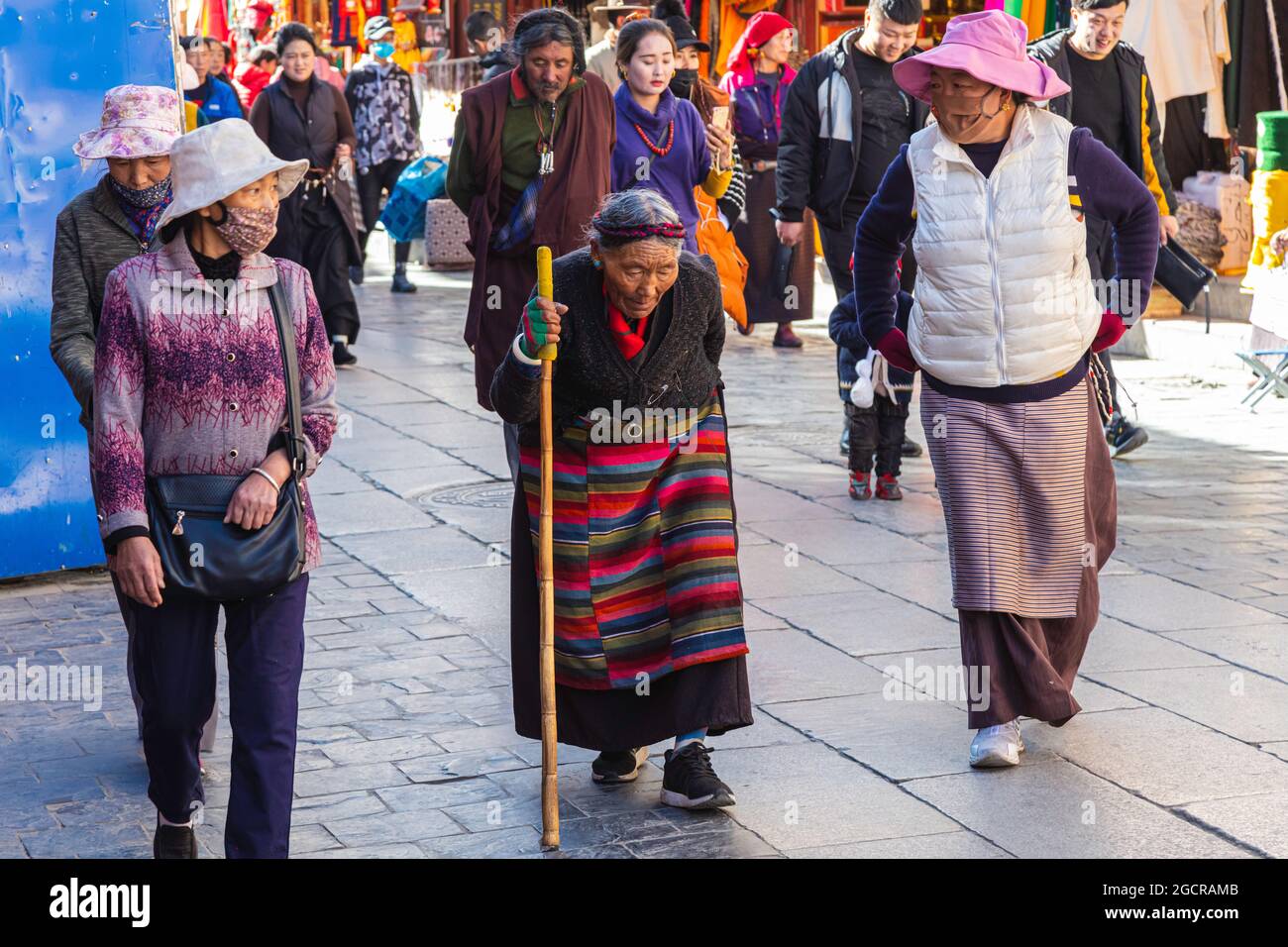 Lhasa, Tibet, China - November 15, 2020:  Old Tibetan woman in traditional Tibetan clothes and walking stick. For prayer purpose people walking on the Stock Photo