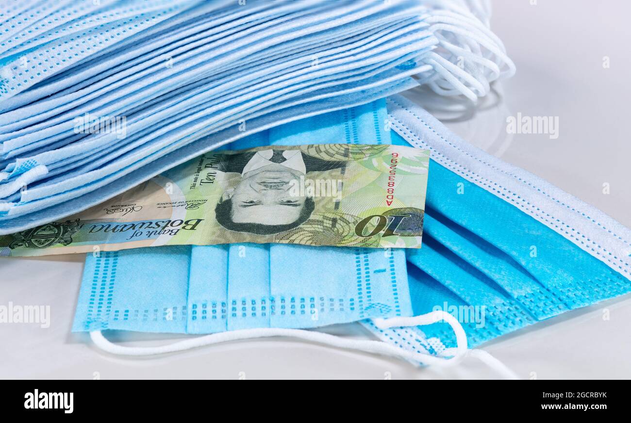Face masks and Pula of Botswana on white background. Face mask the new world currency. Corona virus let  price rising high for mouth protection. Close Stock Photo