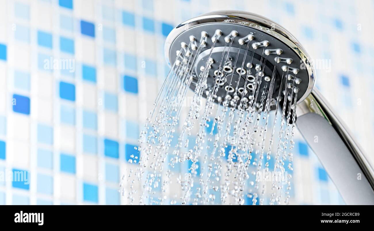 Shower head with running water in blue bathroom Stock Photo - Alamy