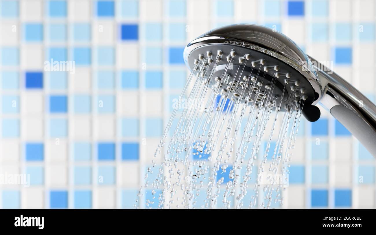 Shower head with flowing water stream in blue bathroom Stock Photo - Alamy