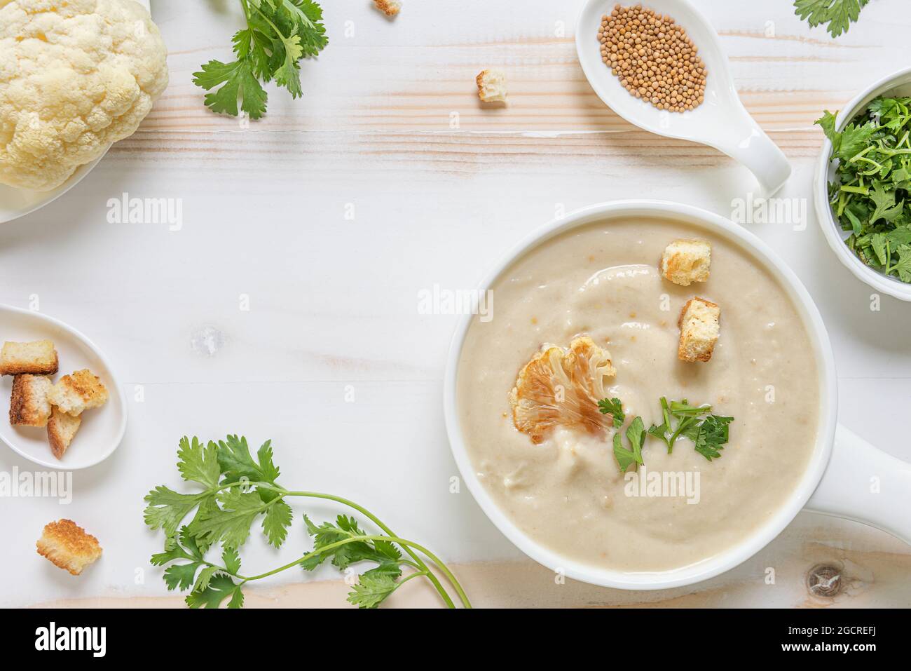 Cauliflower cream soup with fresh green herbs and croutons in white ...