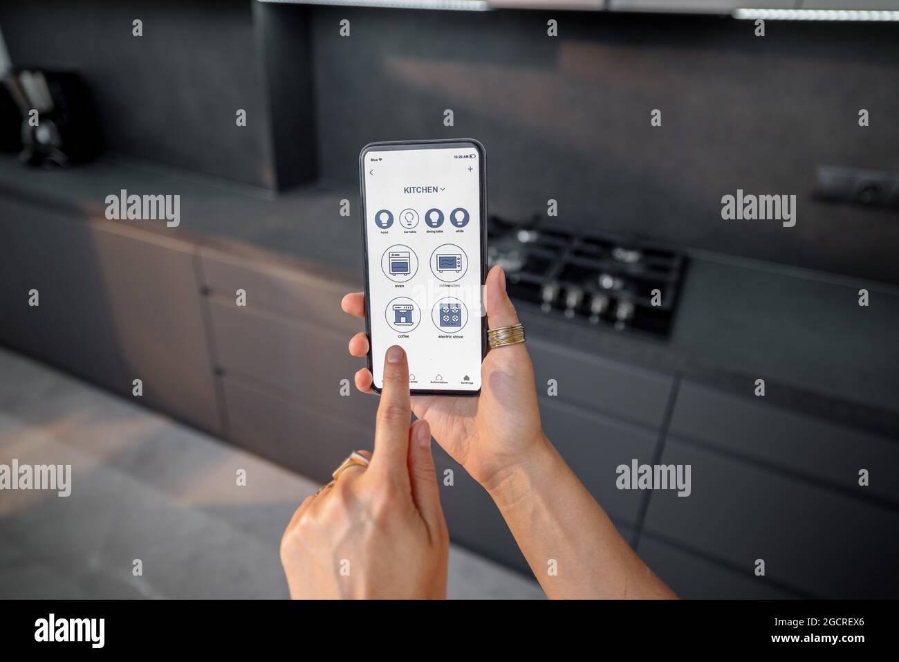 Controlling smart devices with phone on the kitchen Stock Photo
