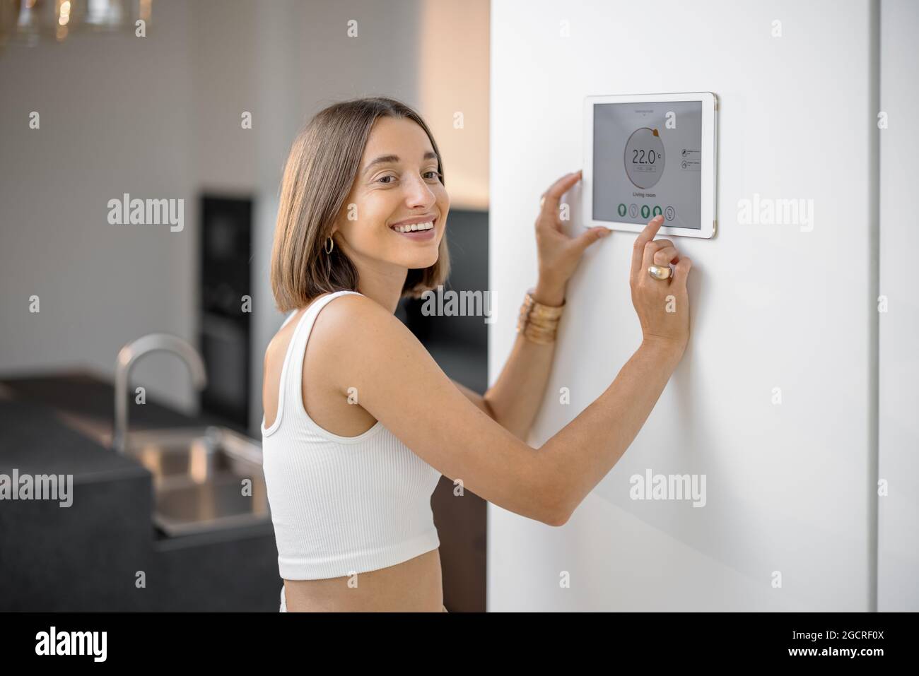 Happy woman controlling smart devices using control panel at kitchen ...