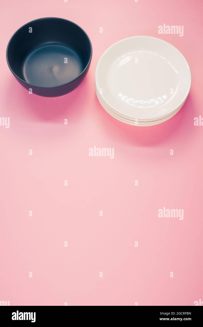 Top view of empty ceramic black and white plates on a pink background ...