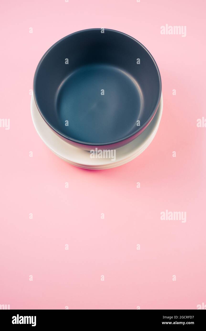 Top view of empty ceramic black and white plates on a pink background ...